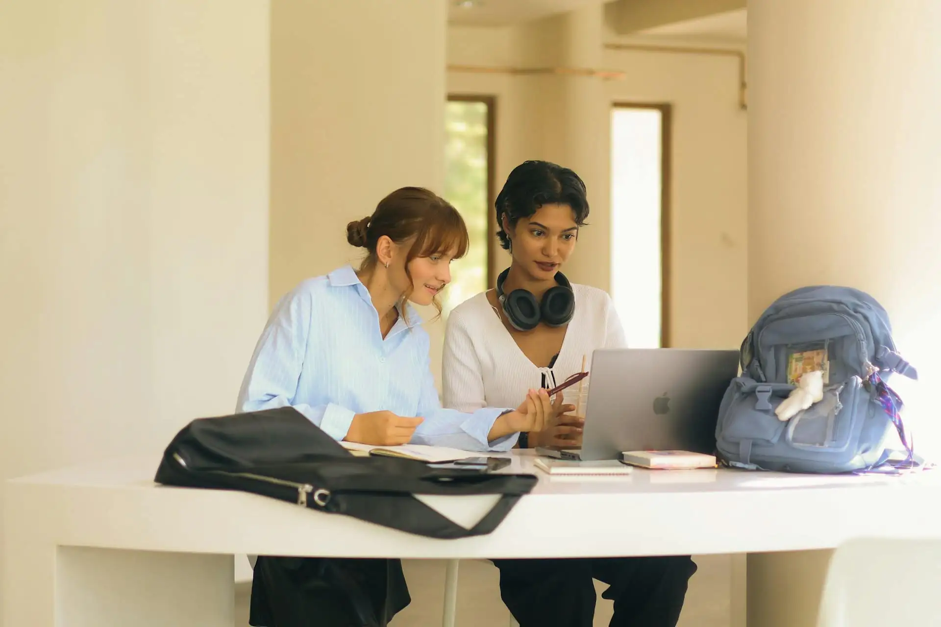 Two students revising together with a laptop and notes