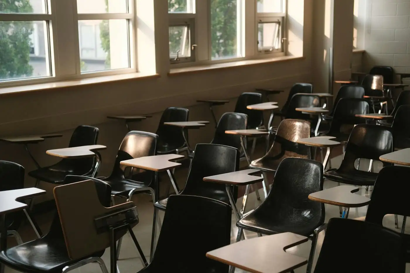 A classroom with rows of desks and chairs by large windows