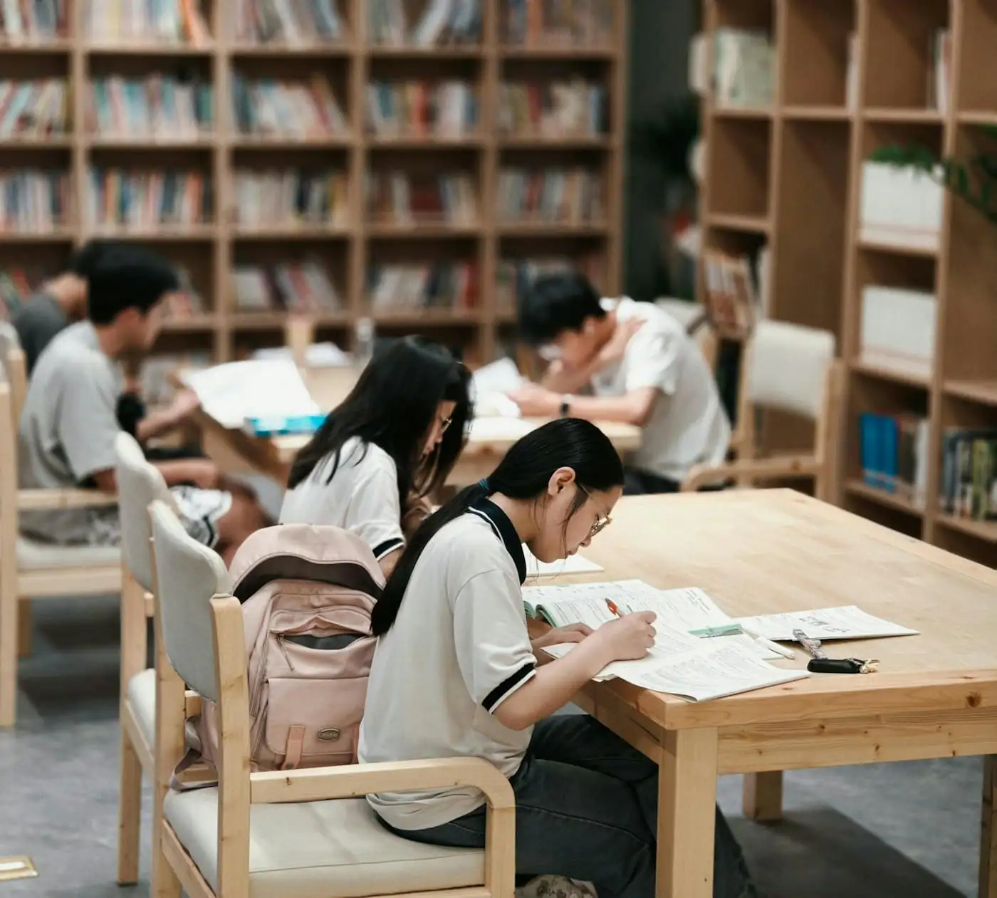 Students studying at tables in front of bookshelves