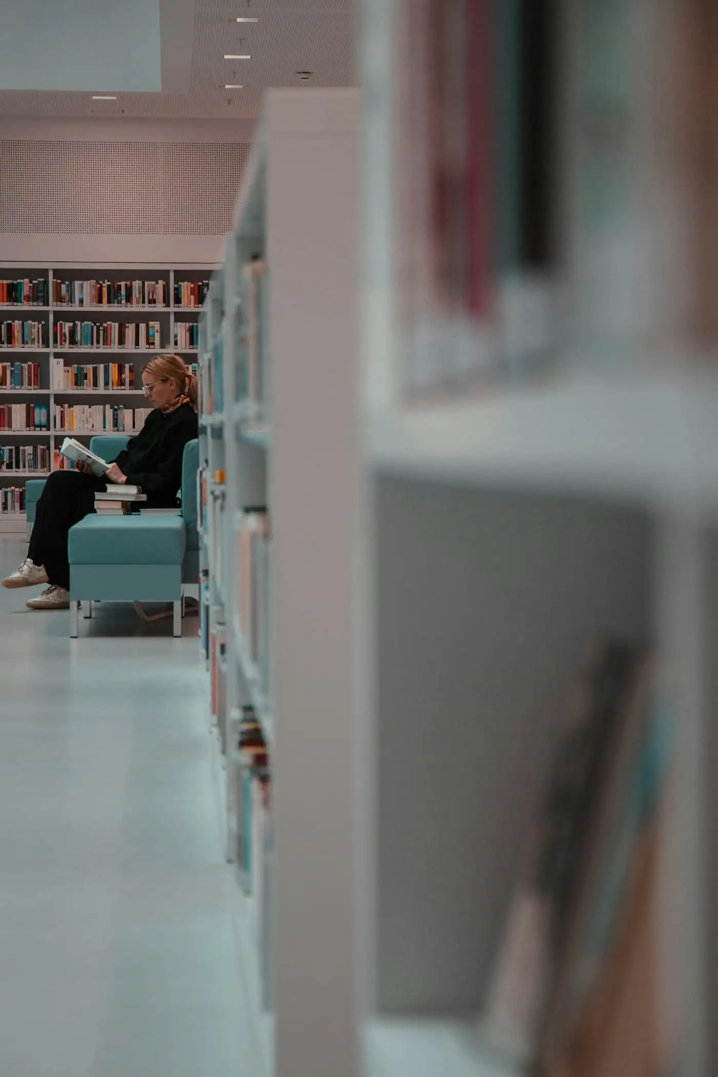 Student reading in a library corner with bookshelves