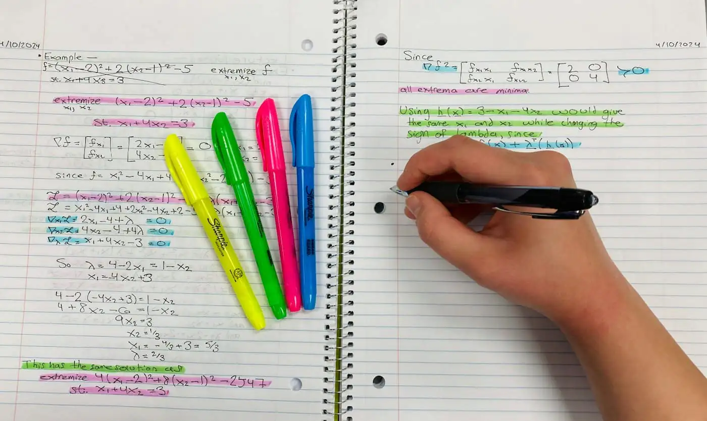 Hand writing revision notes beside coloured highlighter pens