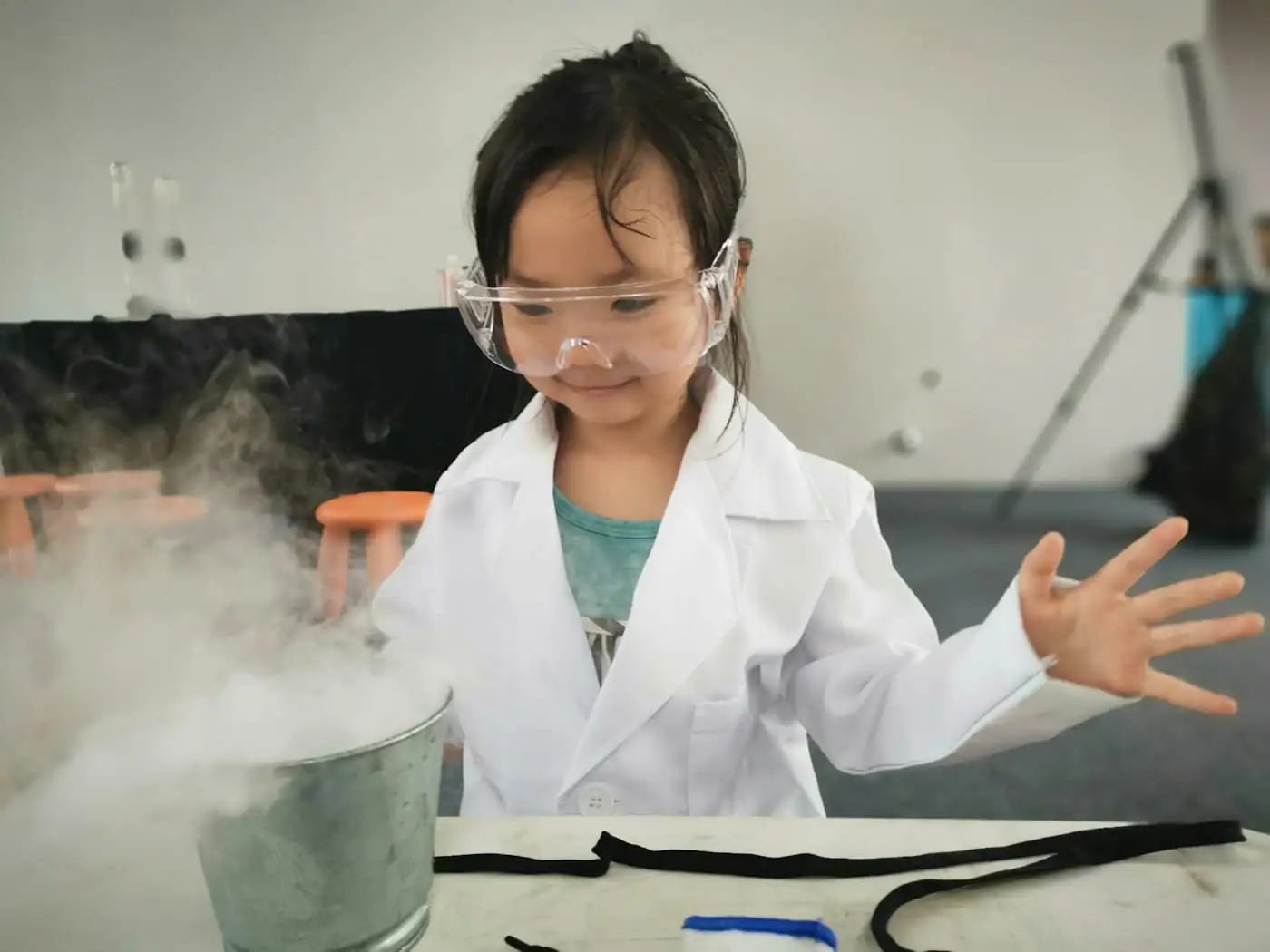 Girl in a lab coat and safety goggles at a science demonstration